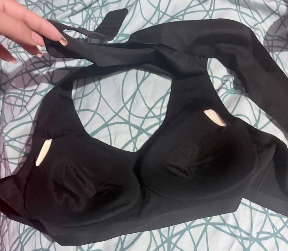 A black garment or clothing item laid out on a bed with patterned bedding
