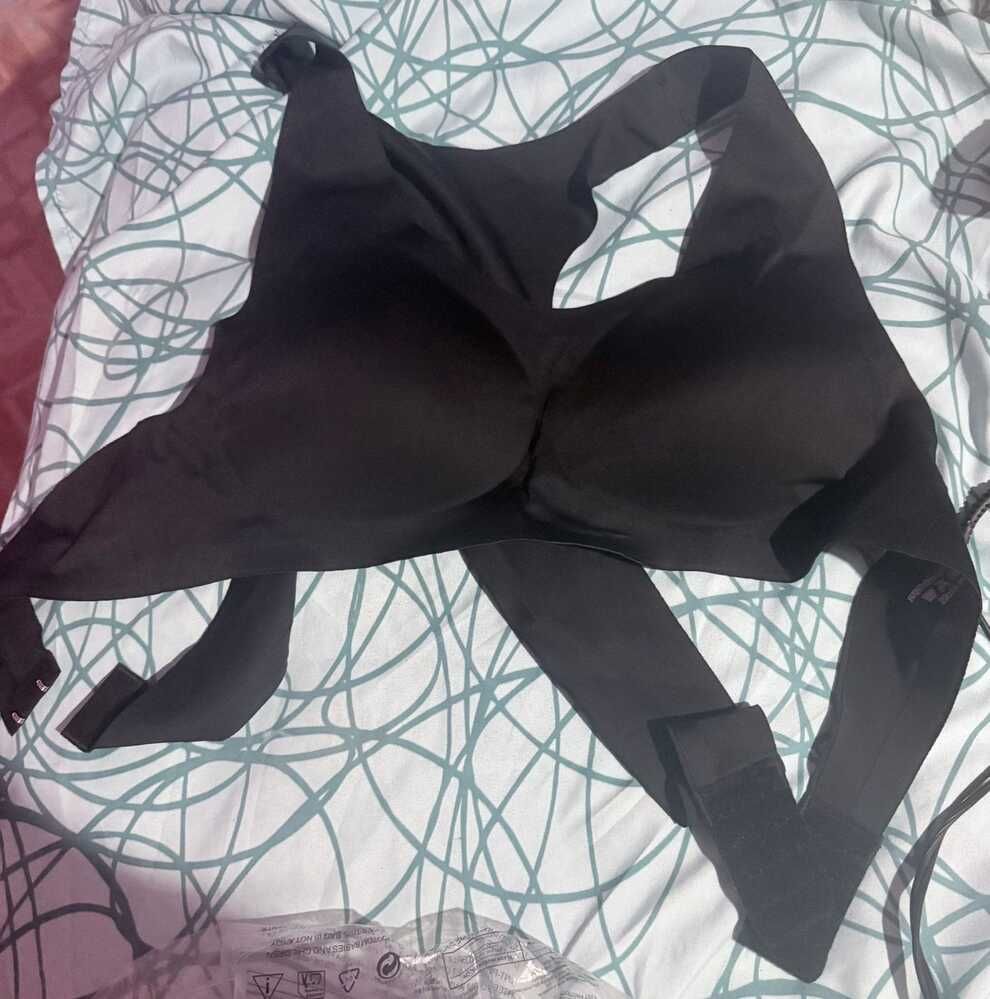 A black garment or clothing item laid out on bedding with a geometric pattern