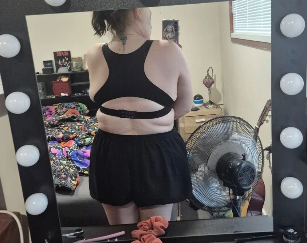 Person taking a mirror selfie in a bedroom wearing casual black clothing