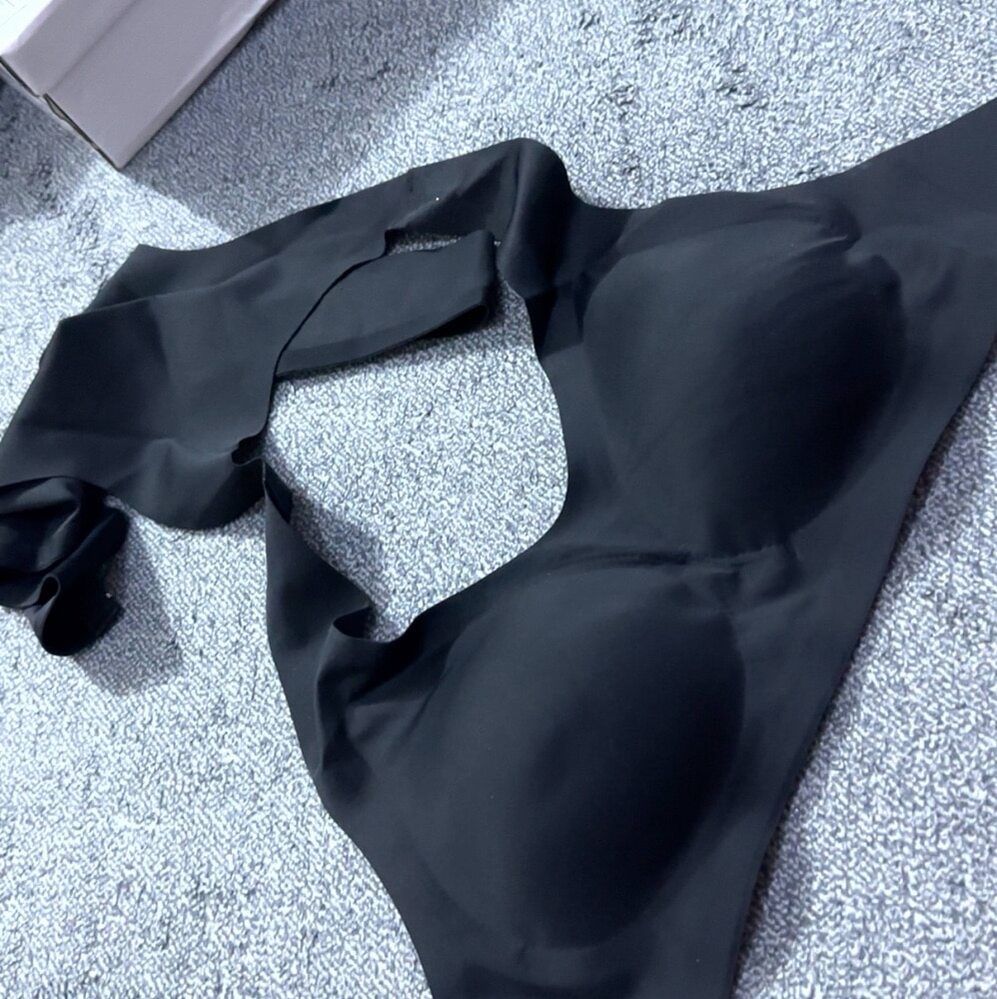 A black garment or clothing item laid out on a gray textured carpet surface