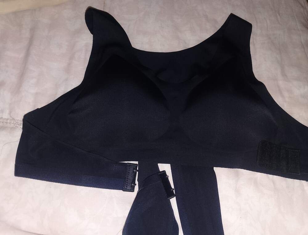 A black sleeveless garment or top laid flat on white bedding