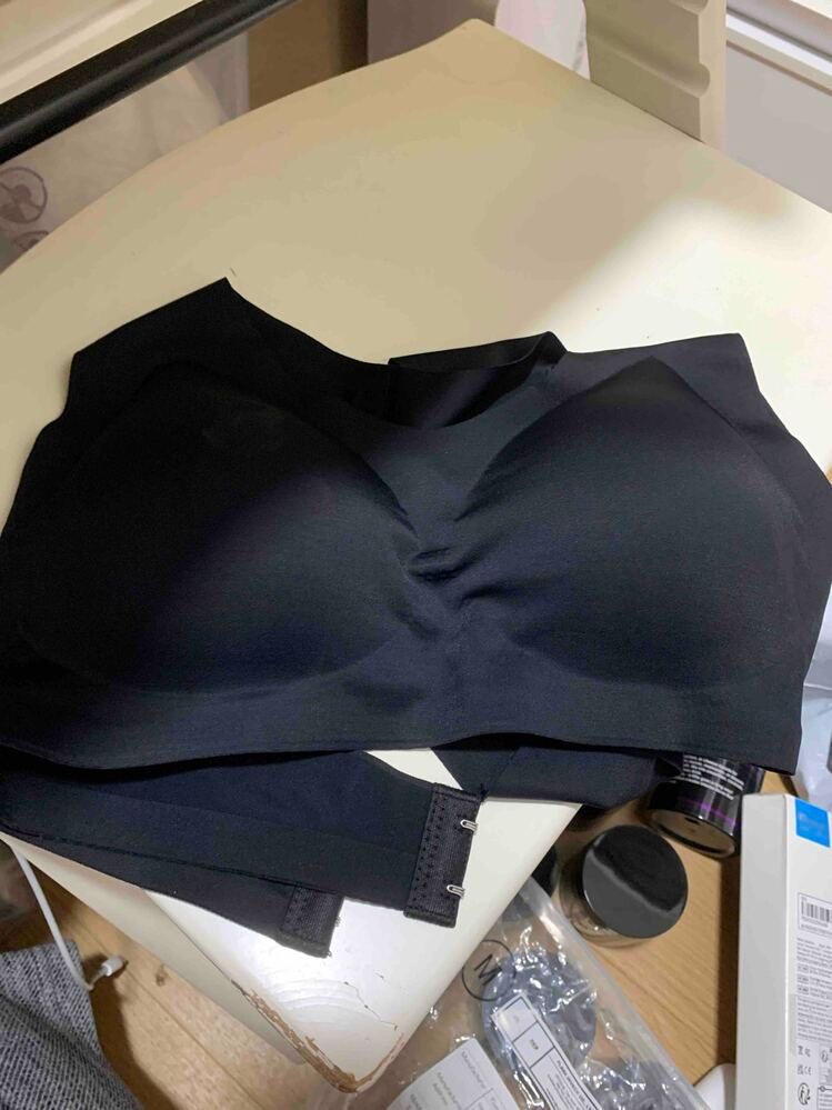 Black bra or undergarment laid out on a light-colored surface with various items nearby