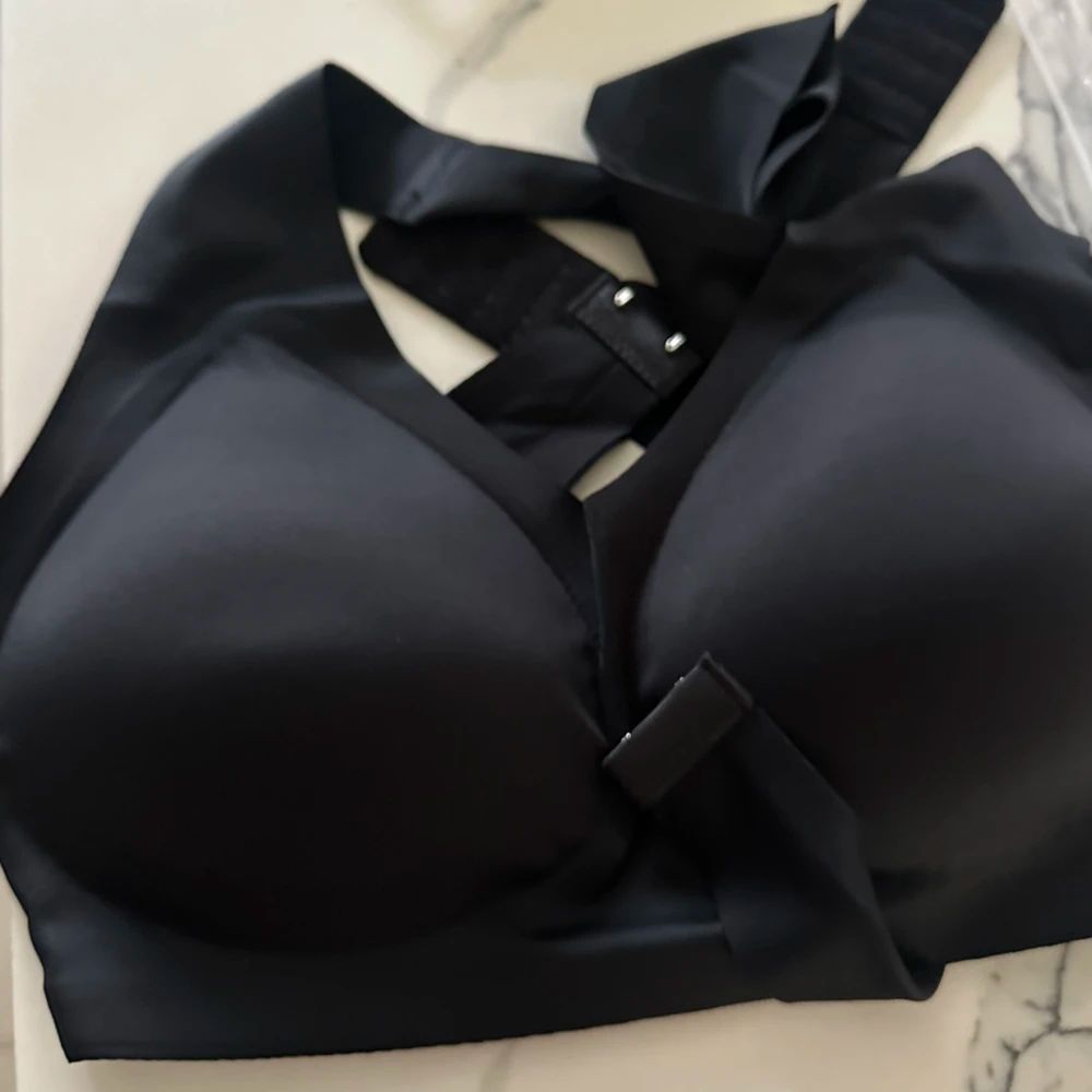 Black sports bra or athletic top with adjustable straps laid flat on white bedding