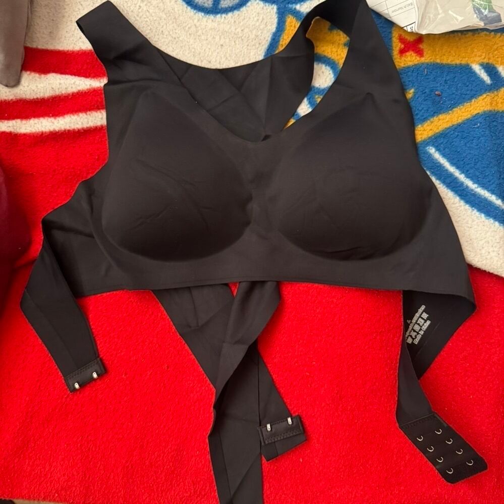 Black sports bra or athletic top with adjustable straps laid out on a red and white striped surface