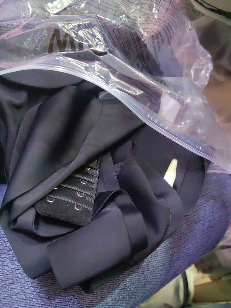 A dark colored bra or undergarment in clear plastic packaging