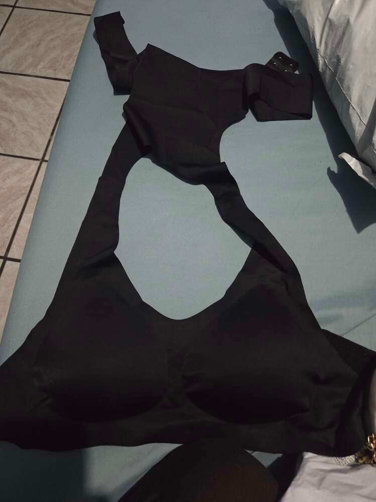 Black clothing or fabric laid out on a light blue surface near tiled flooring