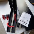 Black metal drywall mount with red clamps and installation instructions on white surface