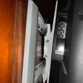 A flat screen TV or monitor mounted on a white wall bracket, showing the side view with visible connection ports and mounting hardware
