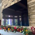 Stone fireplace with mounted TV above wooden mantel decorated with colorful autumn flowers and foliage
