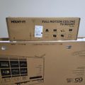 Two cardboard boxes stacked on top of each other - the top box is a Mount-It full motion ceiling TV mount and the bottom box appears to be a Roku TV with various streaming service logos visible on the packaging