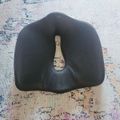 A dark cushion or pillow with a champagne bottle design on it, placed on a patterned rug or carpet