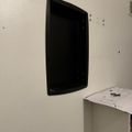 A black flat-screen TV mounted on a white wall above a white desk or table surface