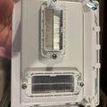 White electronic device case opened to show internal components with metal brush-like elements and circuit boards