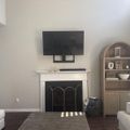 Modern living room with white fireplace, mounted TV, built-in wooden bookshelf, and light-colored furniture