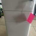 White filing cabinet with three drawers and a lock, featuring a pink sticky note attached to the middle drawer