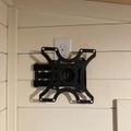 A black TV wall mount bracket installed on a white shiplap wall near an electrical outlet