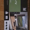 Monoprice full-motion TV wall mount box packaging displayed on a wooden surface, showing product details and specifications for a 32-50 inch television mount with wall anchor extension.