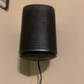 Black Sonos speaker mounted on wall with charging cable