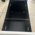 Open drawer of white storage cart showing black interior compartments with dividers