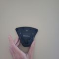 A person's hand holding a dark blue computer mouse with multiple buttons against a white background.