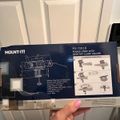 Hand holding a Mount-It power strip with desktop clamp holder product box showing installation instructions and product details
