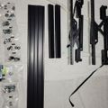 Black metal furniture hardware components and screws laid out on white foam packaging for assembly