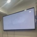 Large flat screen TV mounted on wall in living room with stone accent wall and decorative items on shelves