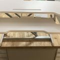 A white adjustable standing desk converter with keyboard tray positioned on a wooden desk surface