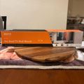 A TV wall mount box sits on a kitchen counter next to a wooden cutting board