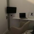 A modern white workspace with a wall-mounted TV, laptop on a floating desk, white chair, and Illinois university poster on the wall