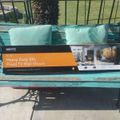 A TV wall mount product box sitting on a turquoise wooden bench outdoors