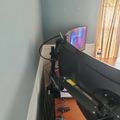 A desk setup with dual black monitors on adjustable arms, with cables visible and a window with blinds in the background