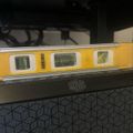 A yellow spirit level tool resting on top of a Cooler Master computer case, showing bubble vials used for measuring levelness