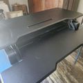 A gray treadmill positioned on wooden flooring in what appears to be a home gym or exercise room with wooden wall panels in the background