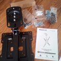 TV ceiling mount kit components laid out on wooden floor including black metal brackets, hardware bags, and instruction manual