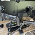A dual monitor desk setup with articulating monitor arms mounted on a wooden desk, with a keyboard and mouse visible on the workspace