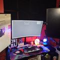Gaming setup with multiple monitors, keyboard, mouse, and colorful LED lighting on a desk in a room with red and black decor