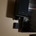 A wall-mounted flat screen TV with a black media console or entertainment center below it in a room with beige walls