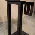 A black metal stand structure with "MOUNTIT!" text on the top panel, featuring vertical supports, a side-mounted bracket, and a base platform.