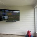 Wall-mounted TV displaying streaming service interface with movie and show options in a room with white wooden plank walls