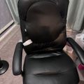 Black leather office chair with lumbar support cushion in a room with gray curtains