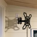 Wall-mounted TV bracket installed on white shiplap wall near electrical outlet