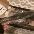 Person unboxing black metal furniture or equipment parts from cardboard packaging on a patterned rug