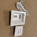 White electronic device with cable and mounting plate on beige carpet