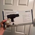 A person holding a product box for a Mount-It power strip with desktop clamp holder against a white paneled door