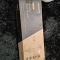 A product box for a monitor desk mount lying on a dark carpet surface