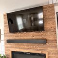 Modern living room wall with mounted flat-screen TV above a soundbar and electric fireplace, all set against a rustic wood plank accent wall