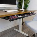 Modern wooden desk with pull-out drawer containing office supplies, white keyboard, computer monitor, and white office chair in contemporary workspace