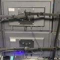 Multiple computer monitors arranged in a grid formation with mounting arms and cables in what appears to be a technical or surveillance setup