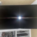 Large flat screen TV mounted on wall above white entertainment center with electronic devices